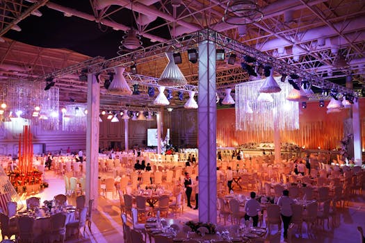 A grand indoor wedding reception with ornate lighting, tables, and a vibrant atmosphere.